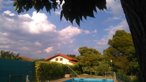 Trees and swimming pool by building against sky