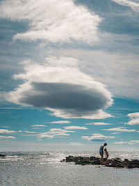 Men standing on beach against sky