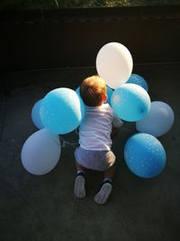 Rear view full length of boy playing with balloons on floor