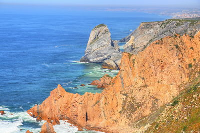 Rock formation on sea shore against sky