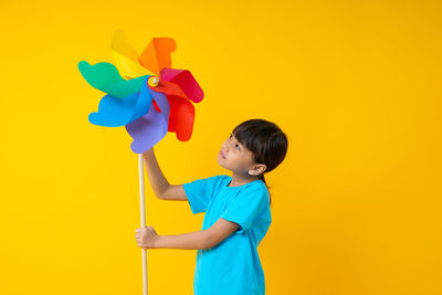 Boy holding toy against yellow background