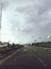 Cars on road against sky seen through car windshield