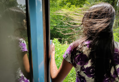 Rear view of woman standing by door in train