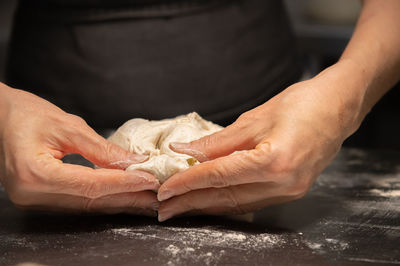 Close-up of female hands kneading dough for making artisan bread at home bakery