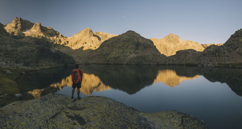 A young man with backpack looking at lake reflection, sierra de gredos