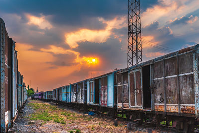 Train on railroad tracks against sky during sunset