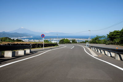 Road leading towards mountain against clear sky