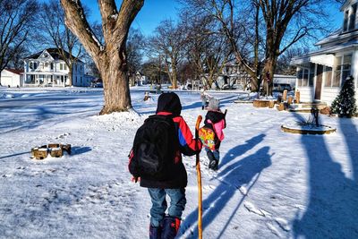 Rear view of boys on snow covered tree