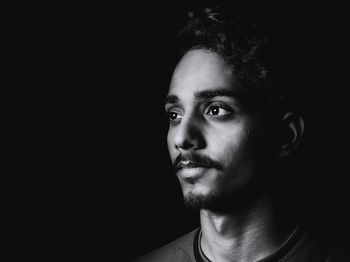 Thoughtful young man against black background