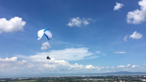 Low angle view of paragliding against blue sky