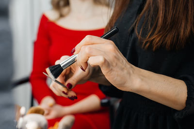 Midsection of woman holding red while sitting in pen