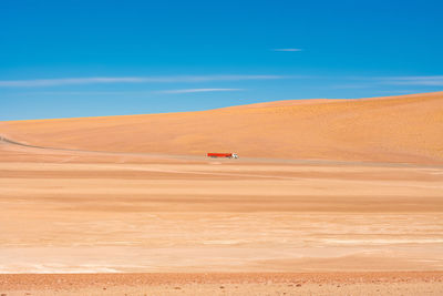 Truck passing through desert against sky