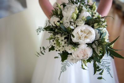 Midsection of bride holding white flowers bouquet