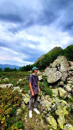 Man standing on rock against sky