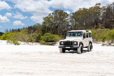 White four-wheel drive off-road vehicle standing on a beach on fraser island, queensland, australia