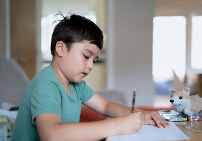 Boy looking at table at home