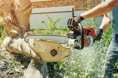 Male worker cuts wood with an electric chainsaw. person