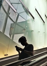 Low angle view of man sitting on glass window