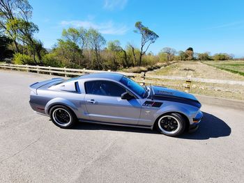 Side view of car on road against blue sky