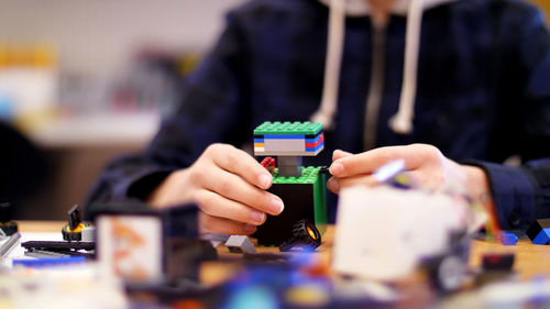 Close-up, children's hands hold a multicolored small robot, machine, assembled from a designer. 