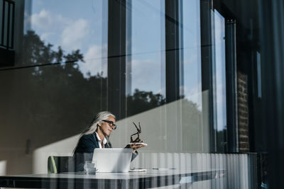 Businesswoman at desk looking at sculpture