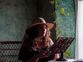 Portrait of woman wearing hat against wall