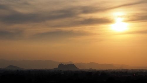 Scenic view of silhouette mountains against orange sky