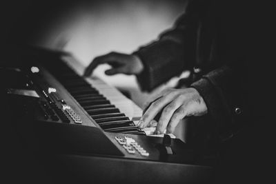 Cropped hands of man playing piano at home