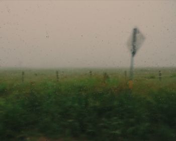 Raindrops on field seen through wet window in rainy season