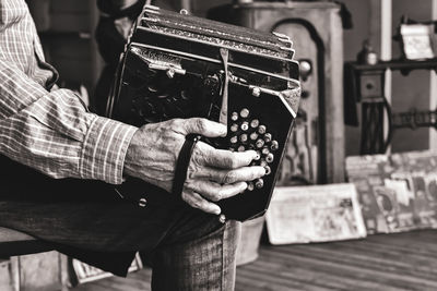 Midsection of man playing accordion while sitting outdoors