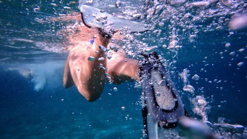 Low section of woman swimming undersea