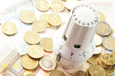 Close-up of thermostat with coins over paper currency notes