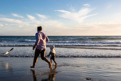 Rear view of man on beach against sky