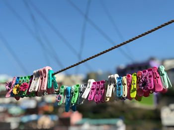 Low angle view of colorful clothespins on clothesline against blue sky during sunny day