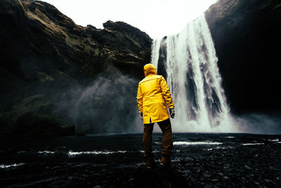 Rear view of man standing at waterfall