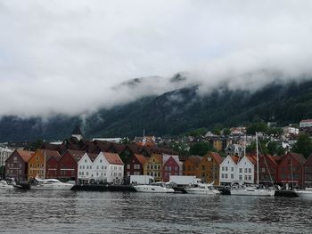 Buildings by river against sky