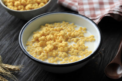 A bowl of star shaped cereal honey star with fresh milk for breakfast. on wooden table