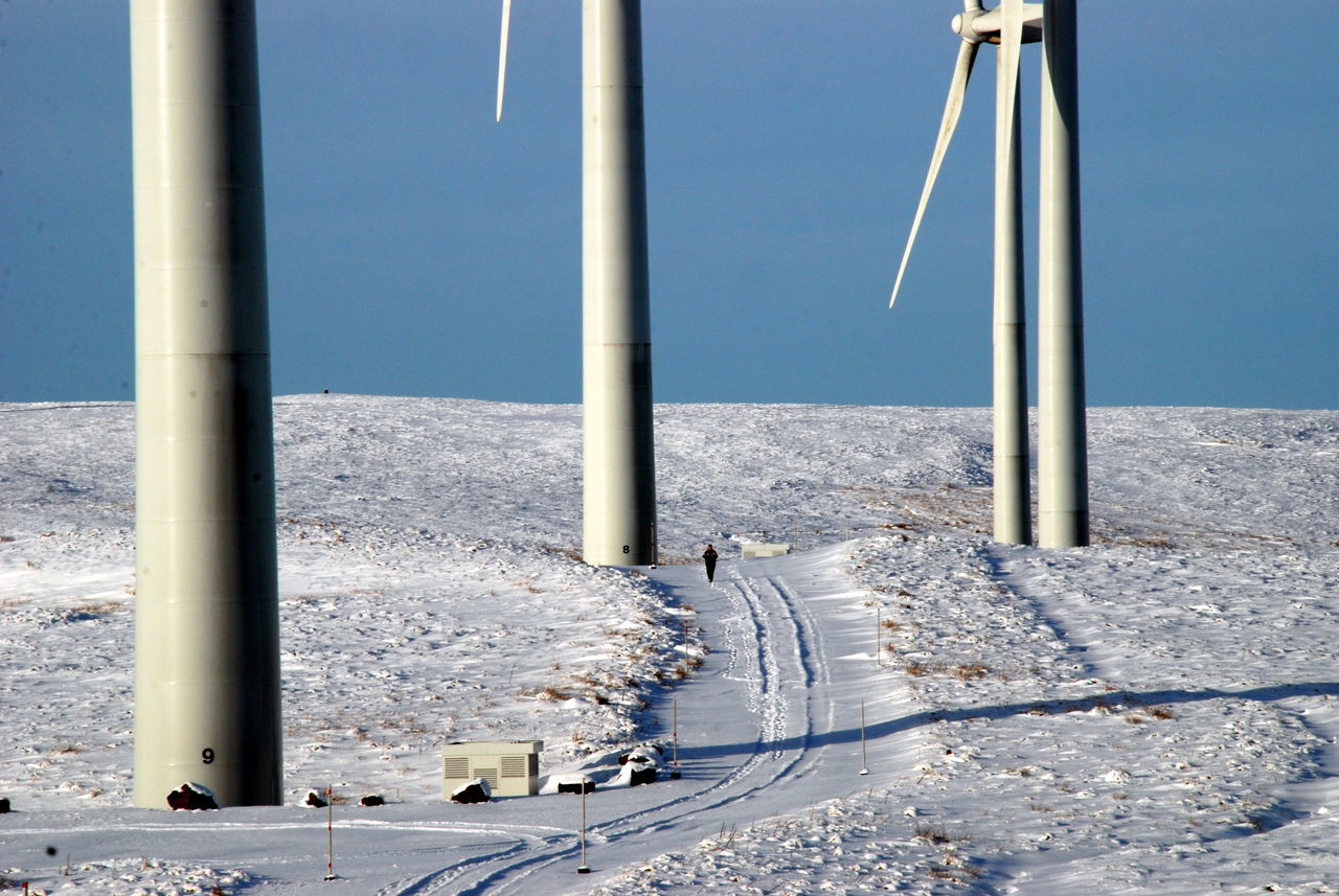 1 person snow shoesx Blue skiesx Wintertimex clean powerx glendevonx man walking through wind farmx renewable energyx snowx wind farmx wind power generatorx wind turbines