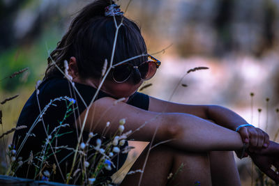 Side view of young woman sitting on field