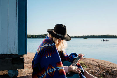 Woman sat playing the guitar at the beach in the sunshine