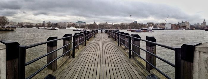 Pier in sea against cloudy sky