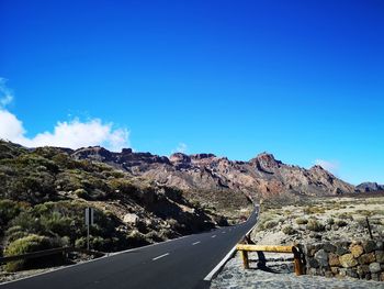 Road by mountains against blue sky