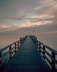 Pier over sea against sky during sunset