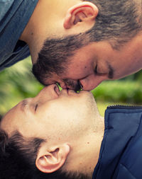 Side view of gay men kissing on mouth at park