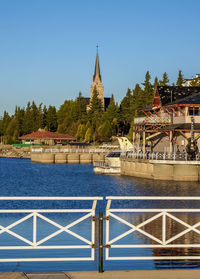 Scenic view of river by building against clear blue sky