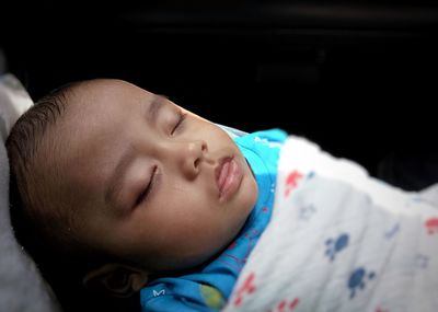 High angle close-up of baby boy sleeping over black background