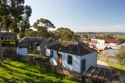 Houses by buildings in town against sky