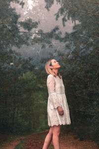 Side view of woman standing in forest