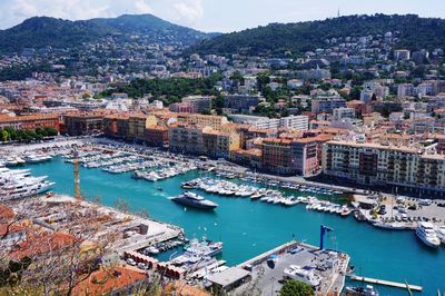 High angle view of boats moored at harbor by buildings in city