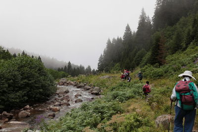 People on road amidst trees and mountains against sky